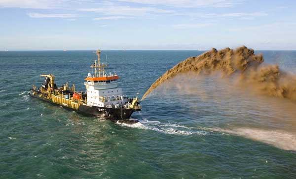 A dredging boat spewing sand in the water